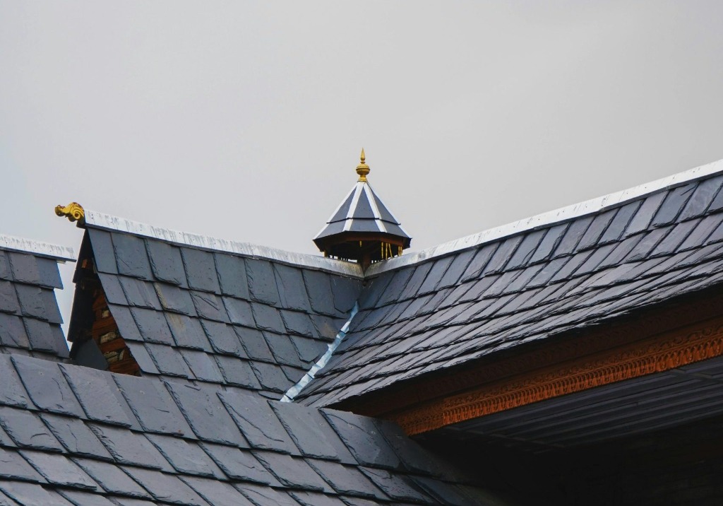 Detailed close-up view of a premium natural slate tile roof featuring custom copper flashing details and finials